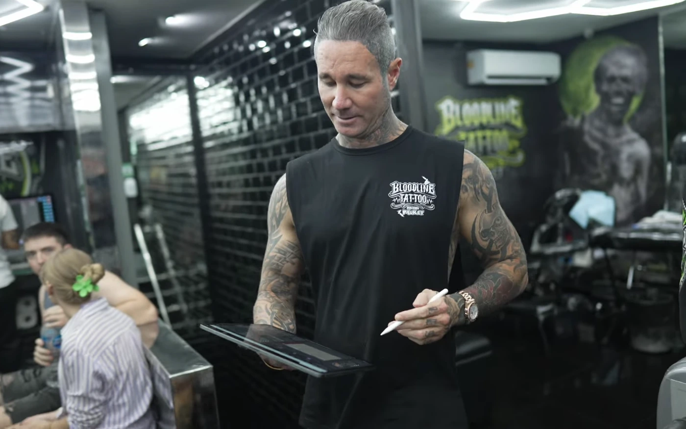 Artist reviewing a digital design on a tablet inside Bloodline Tattoo Phuket