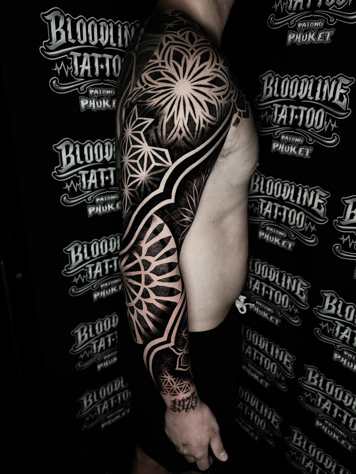 Geometric blackwork full sleeve with asanoha star, mandala circles, and stippled bands on the arm at Bloodline Tattoo Phuket.
