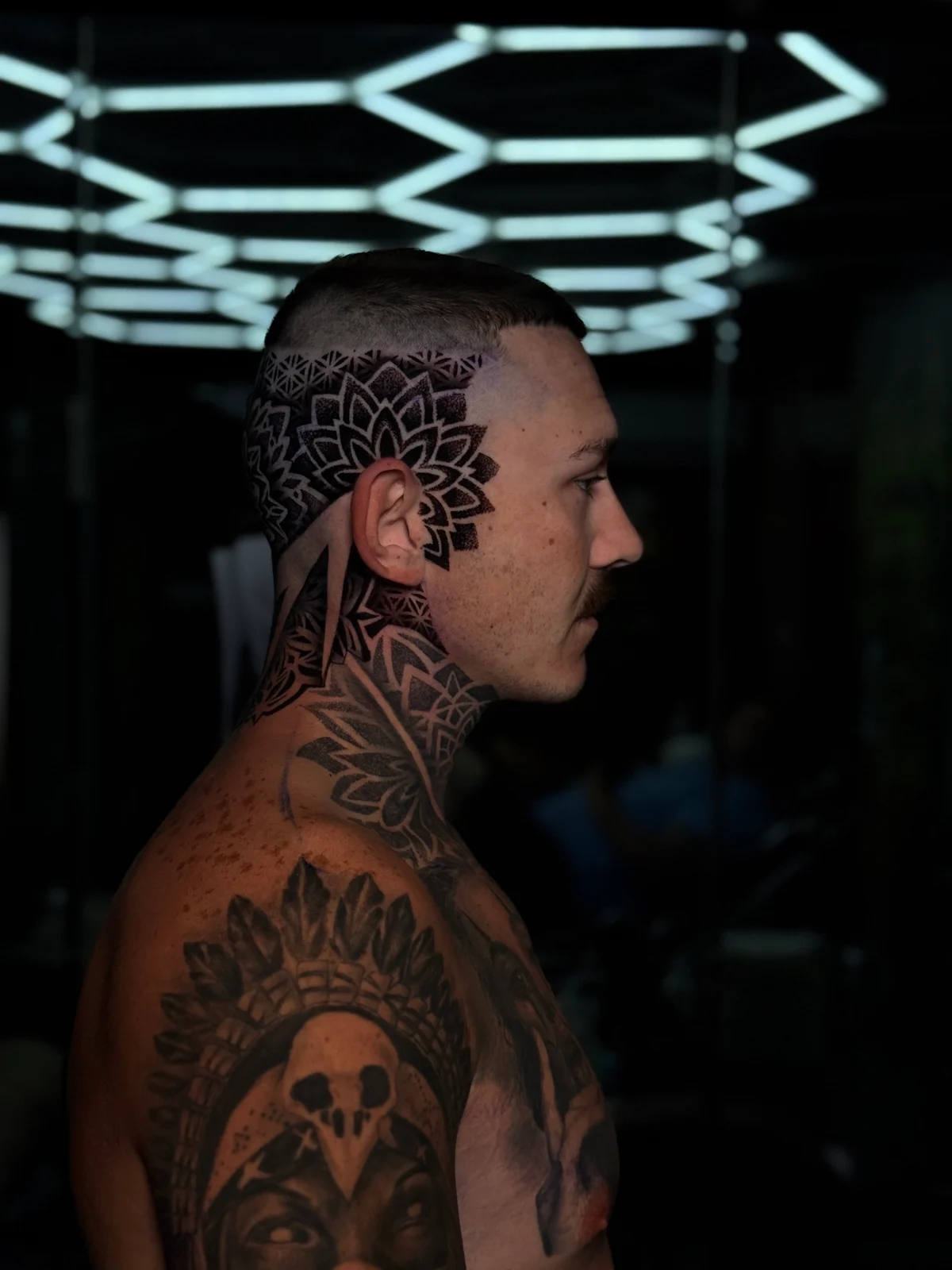 Side-profile head and neck mandala tattoo with a temple lotus mandala transitioning into layered geometric dotwork down the neck, at Bloodline Tattoo Phuket.