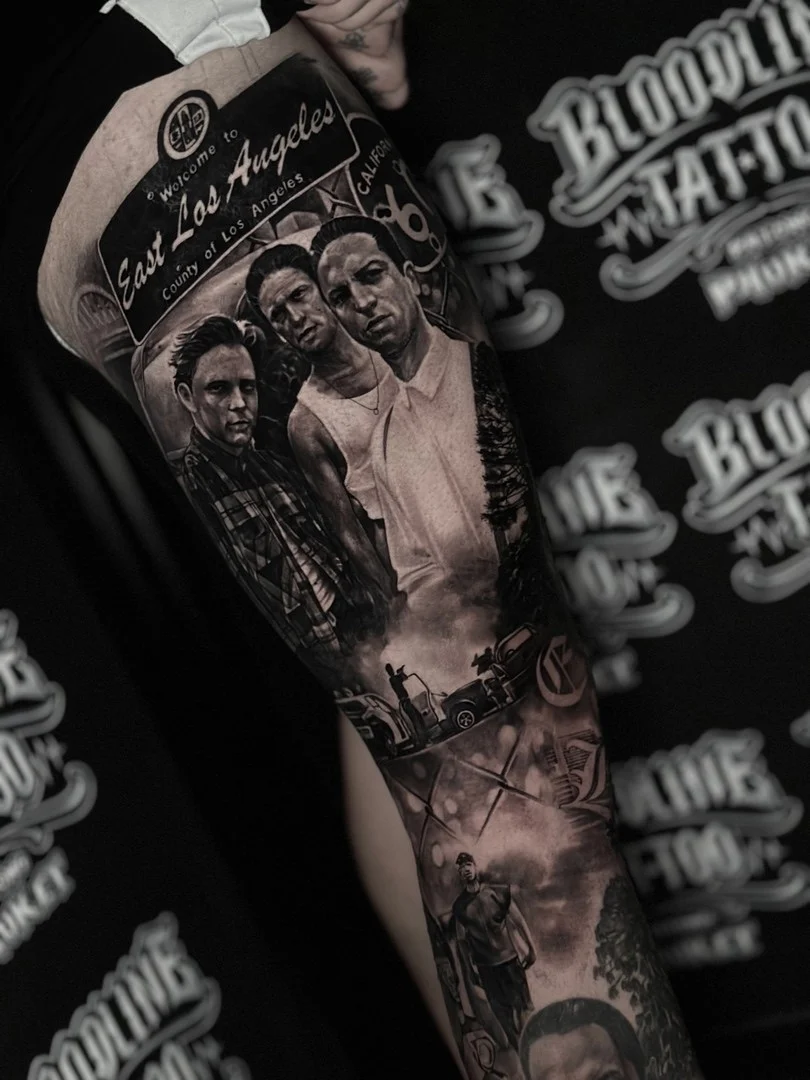 Black and grey portrait realism arm sleeve with East Los Angeles welcome sign and three detailed male portraits at Bloodline Tattoo Phuket.